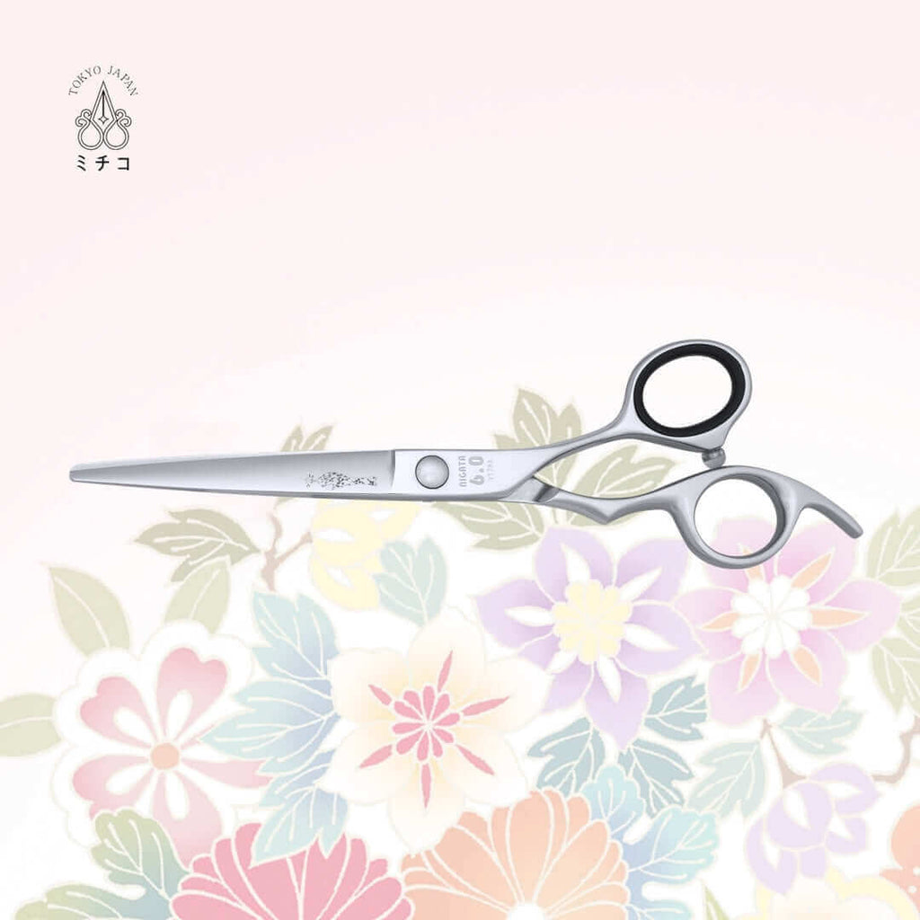 Authentic Japanese NIGATA 6.0-inch salon scissors in a closed position, showing the back side with a traditional Japanese lady in a Kimono as the MICHIKO symbol on the blade. Under the screw area, the model name, size, and serial number are visible.